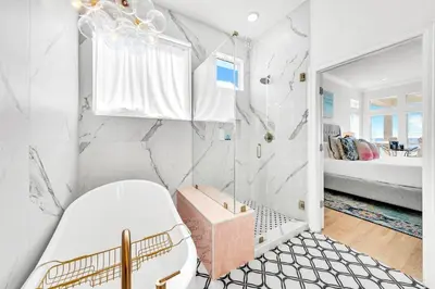a white bathroom with a shower and a bench at Beach Love in Santa Rosa Beach