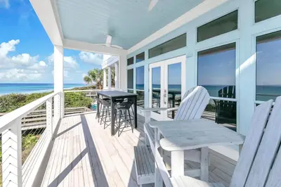 a porch with a table and chairs and the ocean at Beach Love in Santa Rosa Beach