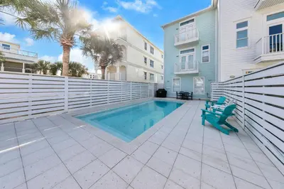a swimming pool in front of a building and a house at Beach Love in Santa Rosa Beach