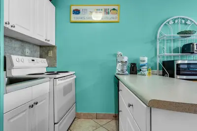 a kitchen with white appliances and a blue wall at Top of the Gulf 210 in Panama City Beach