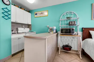 a kitchen with blue walls and a counter with a microwave at Top of the Gulf 210 in Panama City Beach