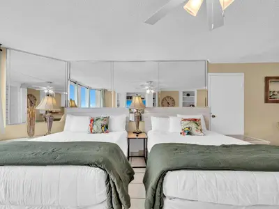two beds in a bedroom with white walls and windows at Top of the Gulf 610 in Panama City Beach