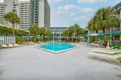 a swimming pool with chairs and palm trees and a building at Nautical Watch E-4 in Panama City Beach
