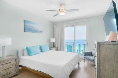 a bedroom with a bed and a balcony with the ocean at Sterling Breeze 1401 in Panama City Beach