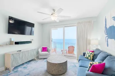 a living room with a blue couch and a tv at Sterling Breeze 1401 in Panama City Beach