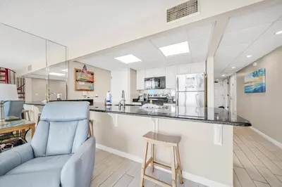 a kitchen with a counter and a blue chair at Edgewater Tower 2-1208 in Panama City Beach