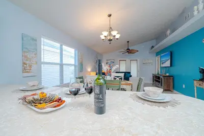 a table with a bottle of wine and two glasses at PALM COVE VACATION HOME- One level, Community pool, Pet Friendly in Panama City Beach