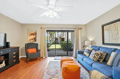 a living room with a blue couch and a ceiling fan at Beachwalk Resort by Panhandle Getaways in Panama City Beach