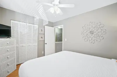 a bedroom with a white bed and a ceiling fan at Beachwalk Resort by Panhandle Getaways in Panama City Beach