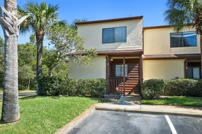 a house with a palm tree and a parking lot at Beachwalk Resort by Panhandle Getaways in Panama City Beach
