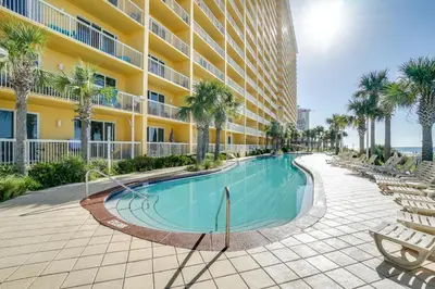 a swimming pool in front of a building with palm trees at Calypso Beach Resort & Towers by Panhandle Getaways in Panama City Beach