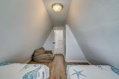 an attic room with two beds and an open door at Cozy 3BRand3BA • Sleeps 9 • 0 3 Mi to Beach • PCB in Panama City Beach
