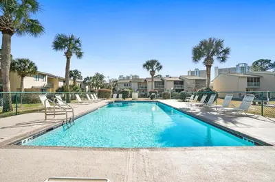 a swimming pool with chairs and palm trees at Gulf Highland Rentals by Panhandle Getaways in Panama City Beach