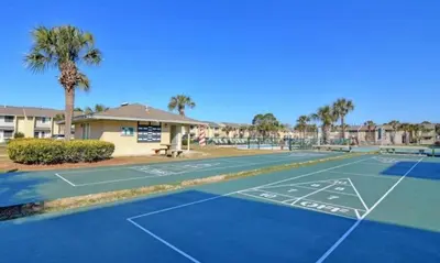 a tennis court in front of a apartment complex at Gulf Highland Rentals by Panhandle Getaways in Panama City Beach