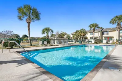a swimming pool with a palm tree and condos at Gulf Highland Rentals by Panhandle Getaways in Panama City Beach