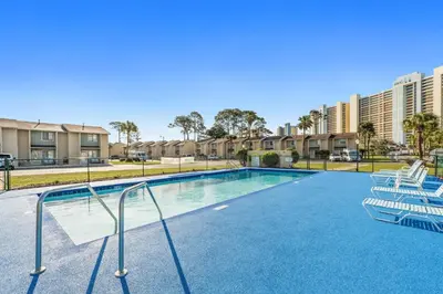 a swimming pool with two chairs and condos at Gulf Highland Rentals by Panhandle Getaways in Panama City Beach