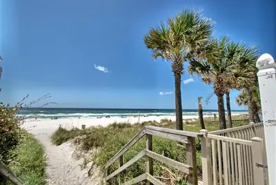 a path to the beach with palm trees and the ocean at Gulf Highland Rentals by Panhandle Getaways in Panama City Beach