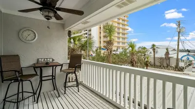 a balcony with a table and chairs and a clock at D’s Beach Retreat – Gulf Views, Hot Tub, Dog-Friendly & Near Schooner’s | Near Beach in Panama City Beach