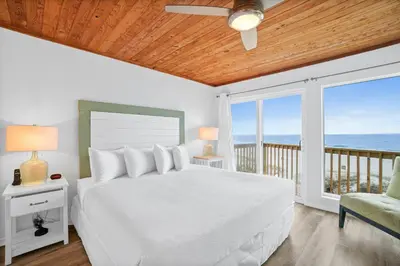 a bedroom with a bed and a balcony with the ocean at Seaward Townhome Rentals by Panhandle Getaways in Panama City Beach