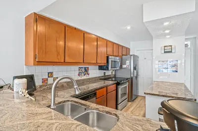 a kitchen with marble counter tops and wooden cabinets at Seaward Townhome Rentals by Panhandle Getaways in Panama City Beach