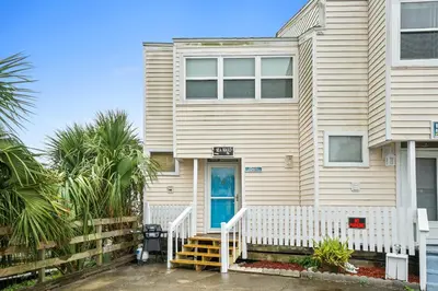 a white house with a blue door at Seaward Townhome Rentals by Panhandle Getaways in Panama City Beach