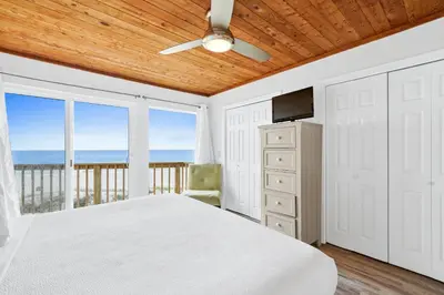 a bedroom with a bed and a balcony with the ocean at Seaward Townhome Rentals by Panhandle Getaways in Panama City Beach