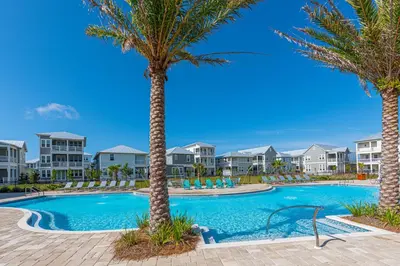 a swimming pool with palm trees and condos at Crab Cottage in Inlet Beach