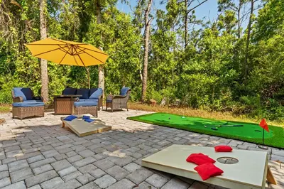 a patio with a ping pong table and an umbrella at Beach bliss awaits! - Beach, Pools, Tiki-Deck, Arcade, Putting green, Family Fun! in Panama City Beach