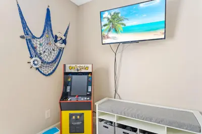 a room with a video game machine and a tv on the wall at Beach bliss awaits! - Beach, Pools, Tiki-Deck, Arcade, Putting green, Family Fun! in Panama City Beach