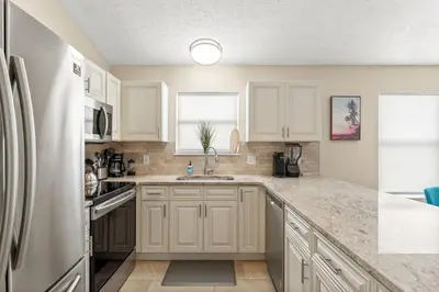 a kitchen with white cabinets and a stainless steel refrigerator at Beach bliss awaits! - Beach, Pools, Tiki-Deck, Arcade, Putting green, Family Fun! in Panama City Beach