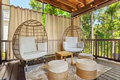 a porch with two swing chairs and a table at Beach bliss awaits! - Beach, Pools, Tiki-Deck, Arcade, Putting green, Family Fun! in Panama City Beach