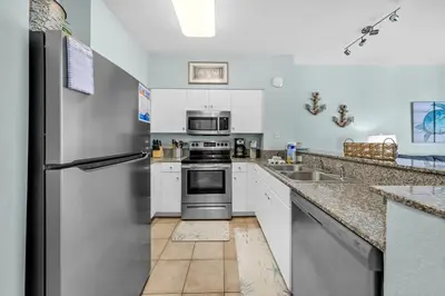 a kitchen with white cabinets and a stainless steel refrigerator at Shores of Panama 1523 in Panama City Beach