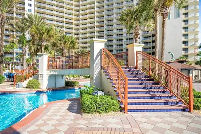 a staircase leading to a pool with palm trees and a building at Shores of Panama 1523 in Panama City Beach