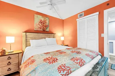 a bedroom with a bed with an orange wall at Sunbird 412E in Panama City Beach