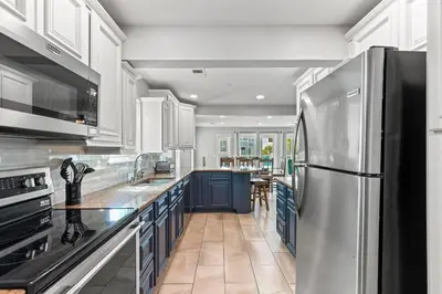 a kitchen with white cabinets and a stainless steel refrigerator at Beach House - Gulf Dream by Panhandle Getaways in Panama City Beach