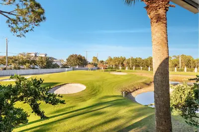 a golf course with a palm tree and a green at Edgewater Gulf Villas 953 in Panama City Beach