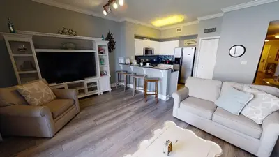 a living room with two couches and a kitchen at Tidewater 3011 in Panama City Beach