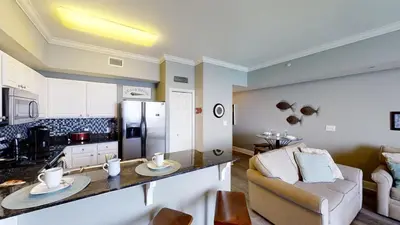 a kitchen and living room with a couch and a refrigerator at Tidewater 3011 in Panama City Beach