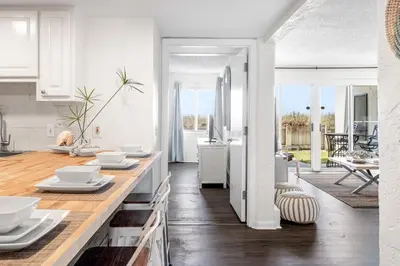 a kitchen with white cabinets and a table with white dishes at Sugar Beach 19C in Panama City Beach