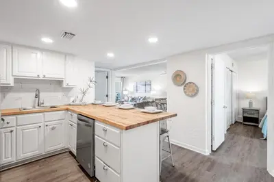 a kitchen with white cabinets and a wooden counter top at Sugar Beach 19C in Panama City Beach
