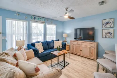 a living room with a blue couch and a tv at Peachtree Place Condominiums by Panhandle Getaways in Panama City Beach