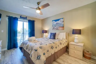a bedroom with a bed with blue curtains and a window at Peachtree Place Condominiums by Panhandle Getaways in Panama City Beach