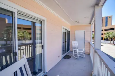 a balcony with sliding glass doors and a chair at Peachtree Place Condominiums by Panhandle Getaways in Panama City Beach