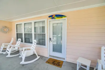 a porch with white chairs on a pink house at Peachtree Place Condominiums by Panhandle Getaways in Panama City Beach