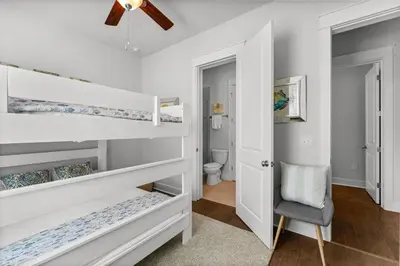 a bedroom with white bunk beds and a ceiling fan at 30A Pet Friendly Beach House - 33 Sunset by Panhandle Getaways in Rosemary Beach