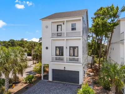 a white house with a garage and palm trees at 30A Pet Friendly Beach House - 33 Sunset by Panhandle Getaways in Rosemary Beach
