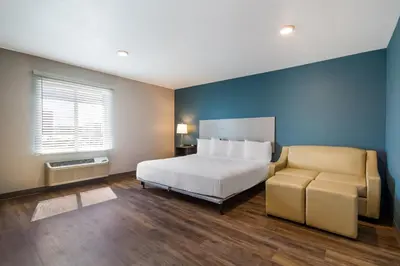 a bedroom with a bed and a couch and a window at WoodSpring Suites Panama City Beach in Panama City Beach