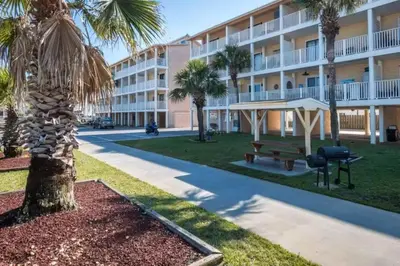 a hotel with a palm tree in front of a building at Across the Street from beach with 2 pools in Panama City Beach