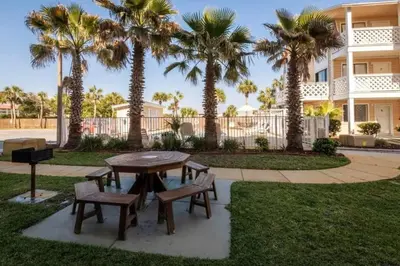 a picnic table and chairs in a park with palm trees at Across the Street from beach with 2 pools in Panama City Beach