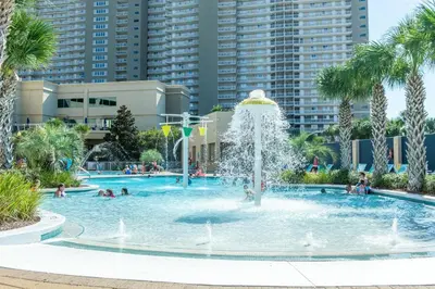 a fountain in a swimming pool with palm trees at Emerald Beach 1035 in Panama City Beach